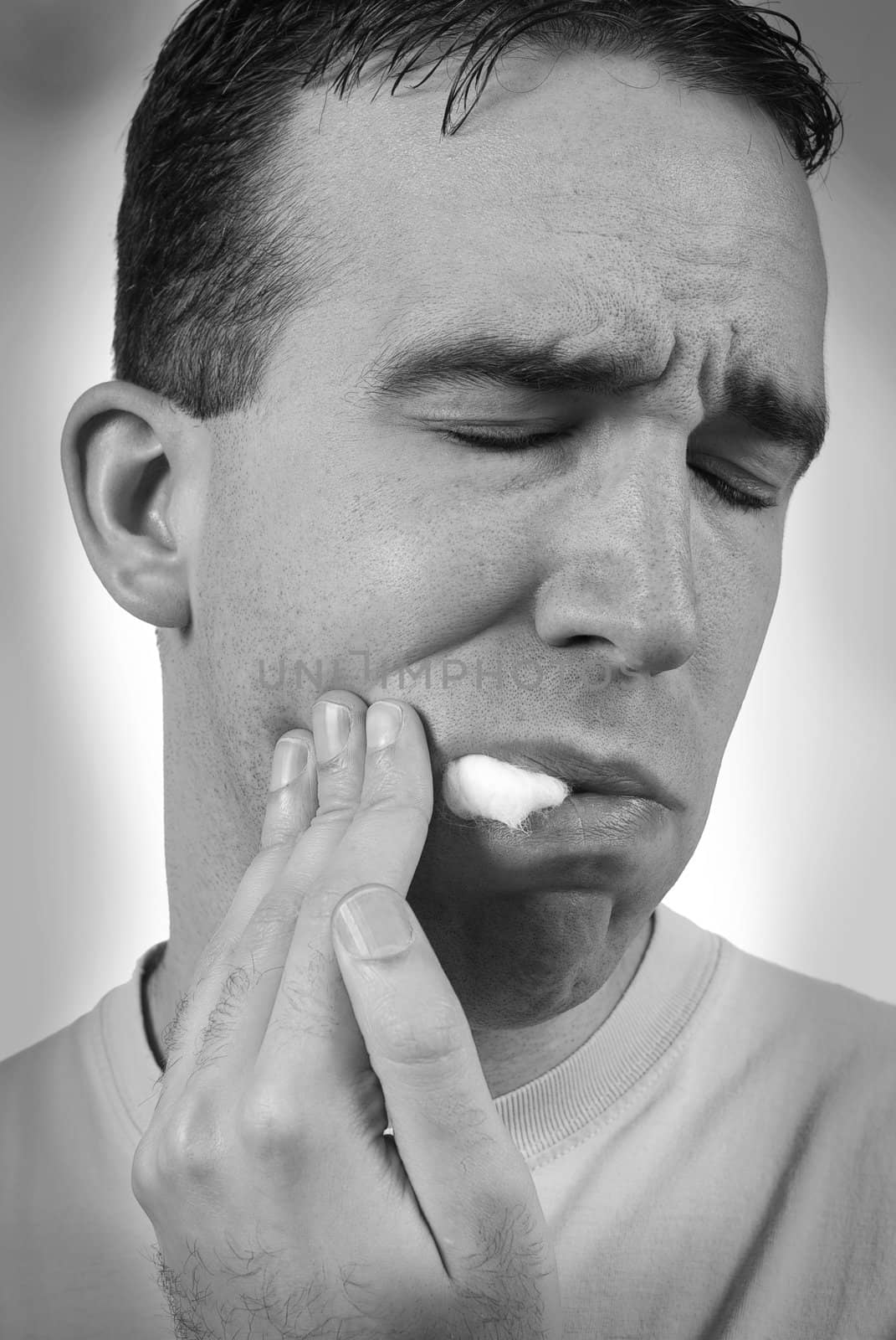 Closeup view of a man with a toothache shot in black and white with a dark vignette around