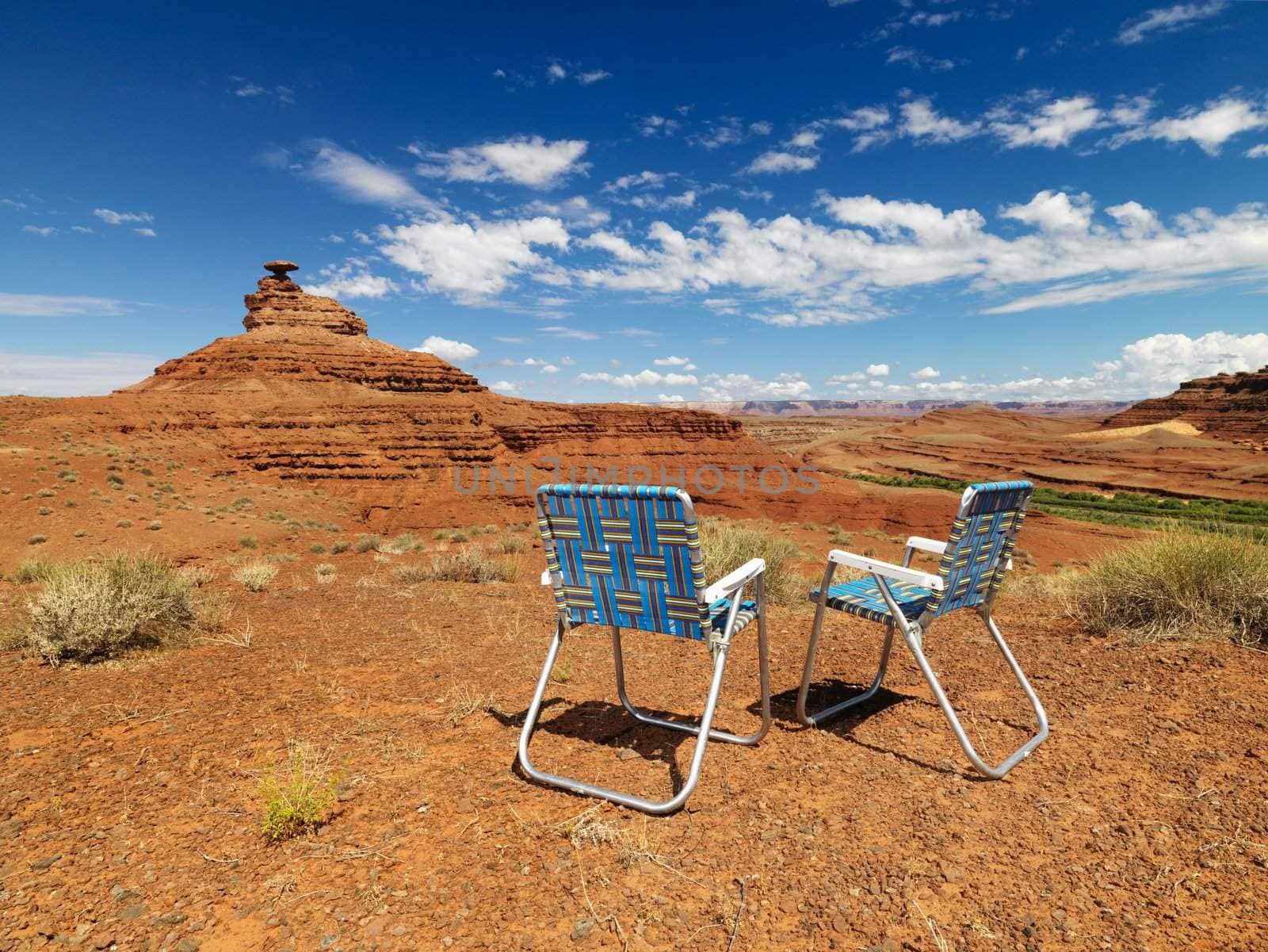 Two lawn chairs in scenic desert landscape with land formation.