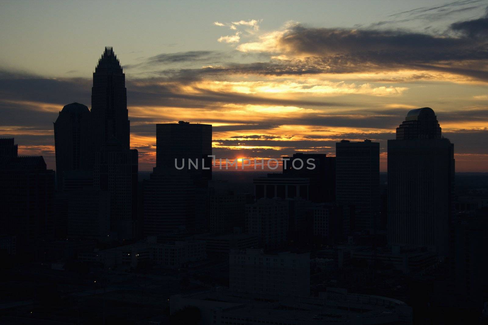 Sunset silhouetting aerial view of Charlotte, North Carolina city skyline.