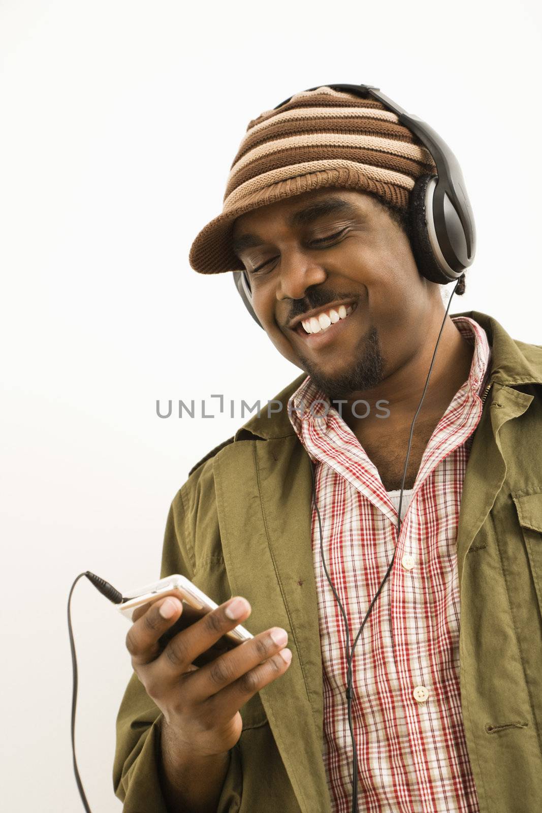 African-American mid-adult man wearing knit hat and listening to headphones and mp3 player.