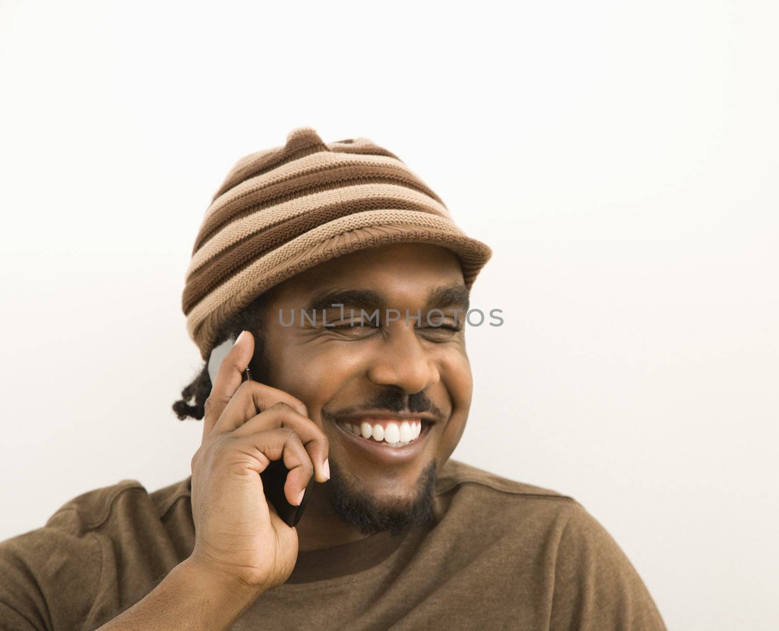 African-American mid-adult man wearing hat talking on cell phone.