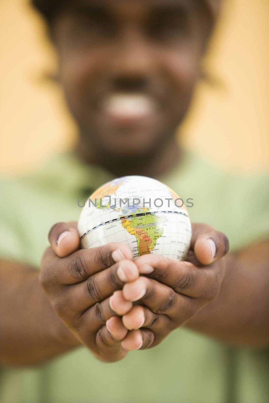 African-American mid-adult man wearing hat holding small globe toviewer.