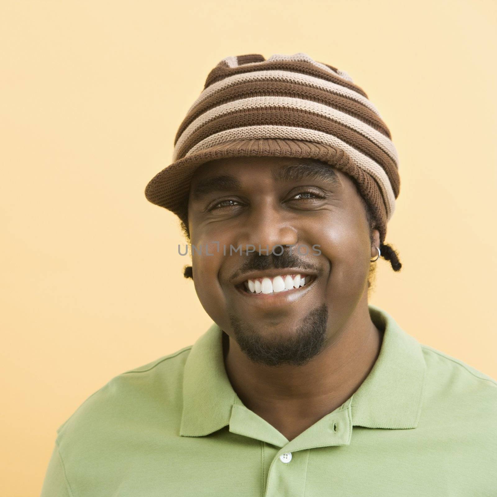 African-American mid-adult man wearing knit hat with brim smiling at viewer.