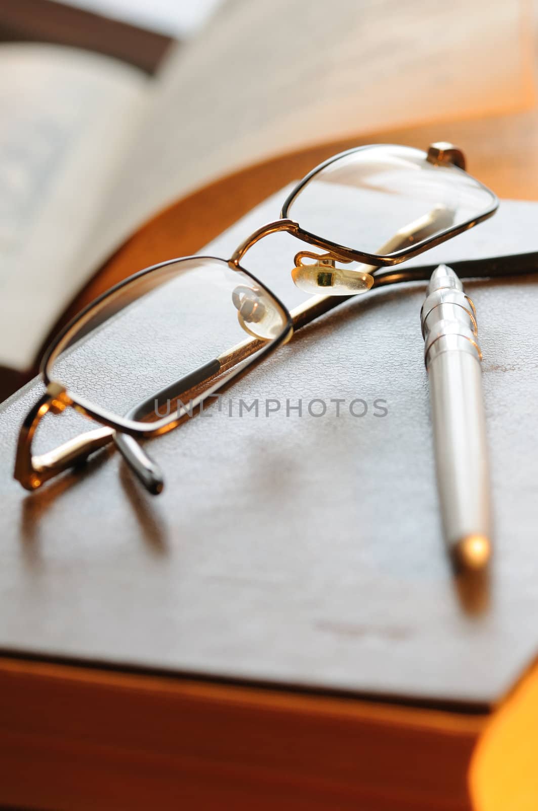 Glasses and the pen lay on the old book