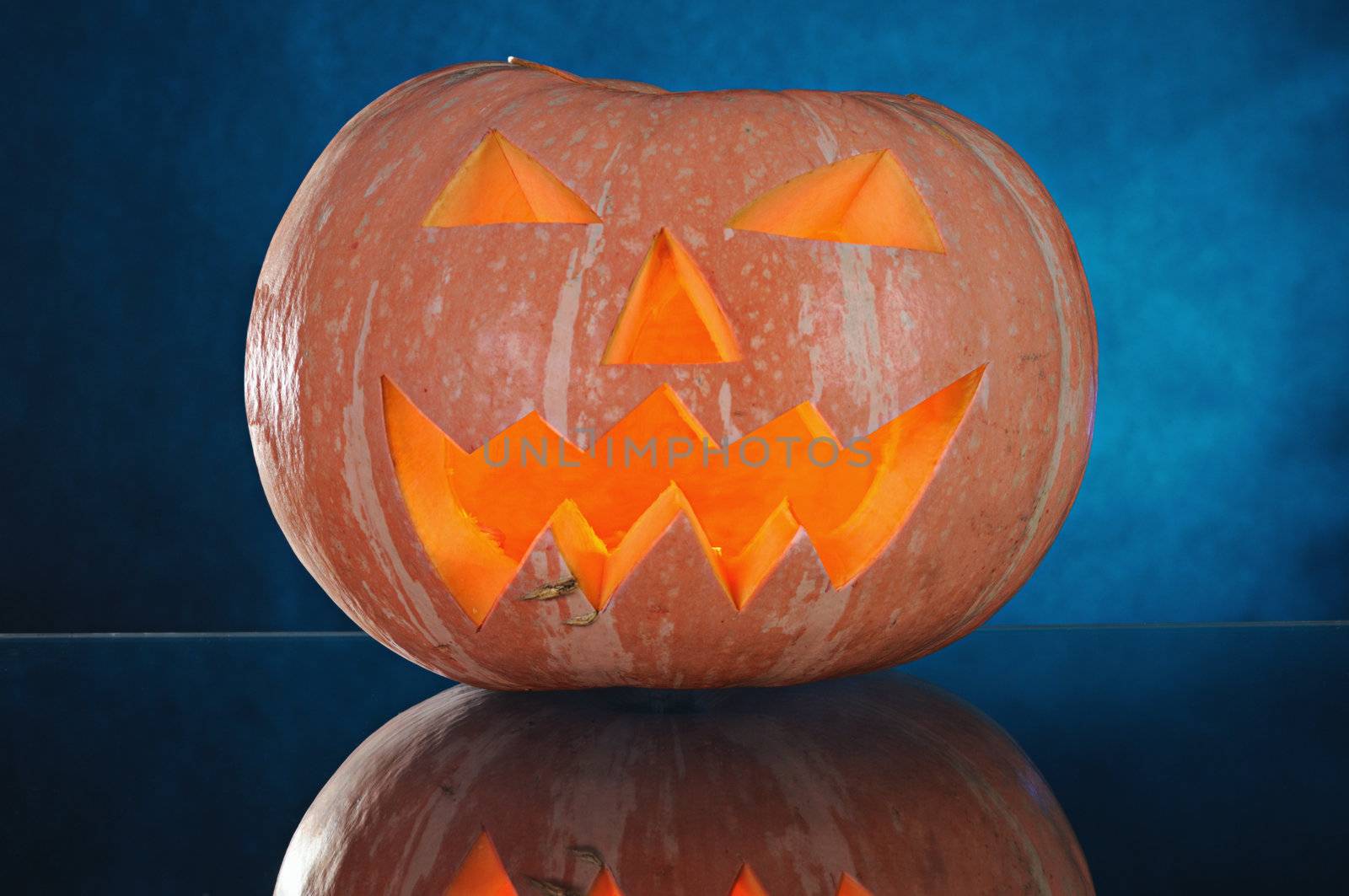  pumpkin with lighting candle inside on blue background