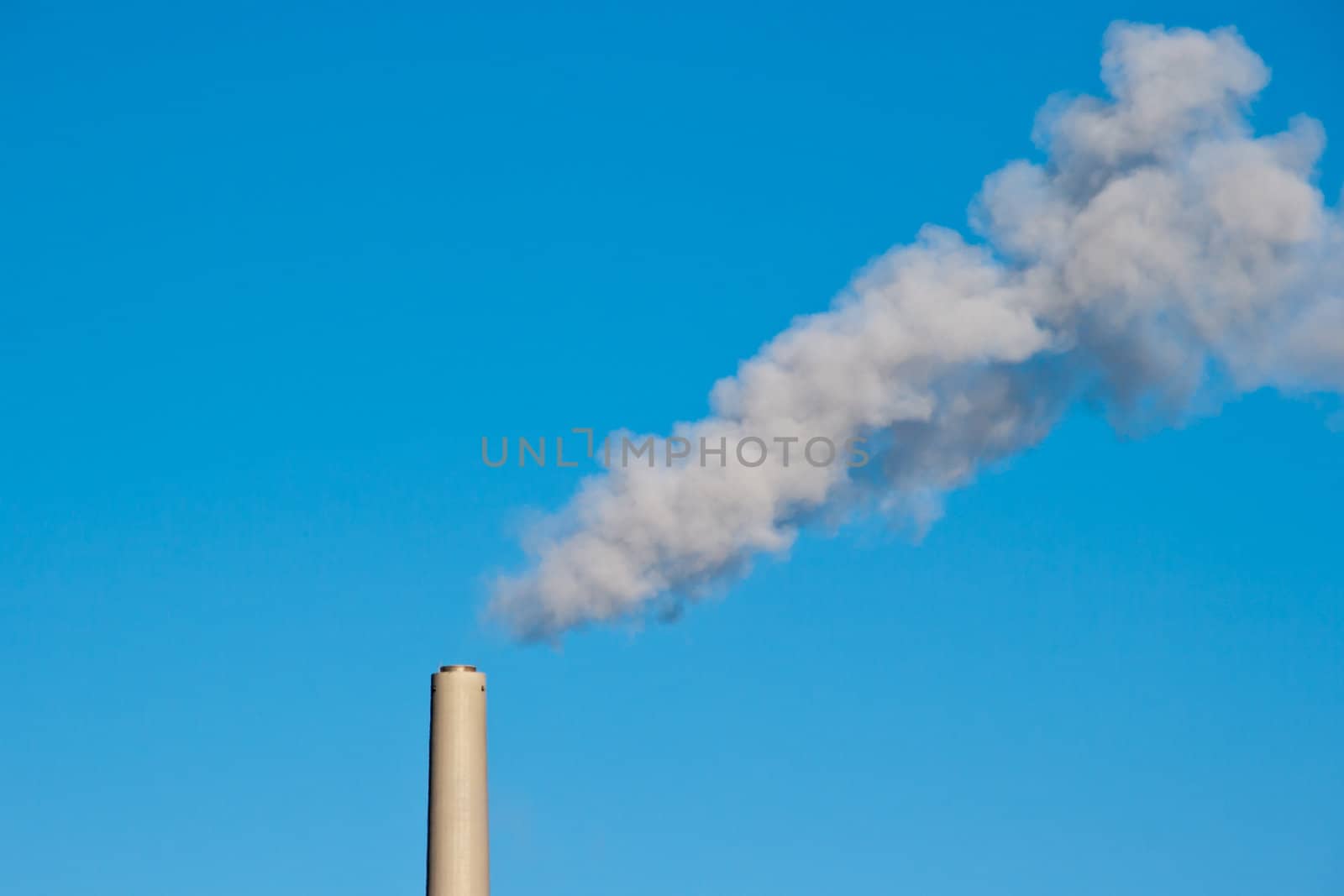 Smoke from coal power plant chimney against blue sky. Symbol of global warming and smoke pollution.
