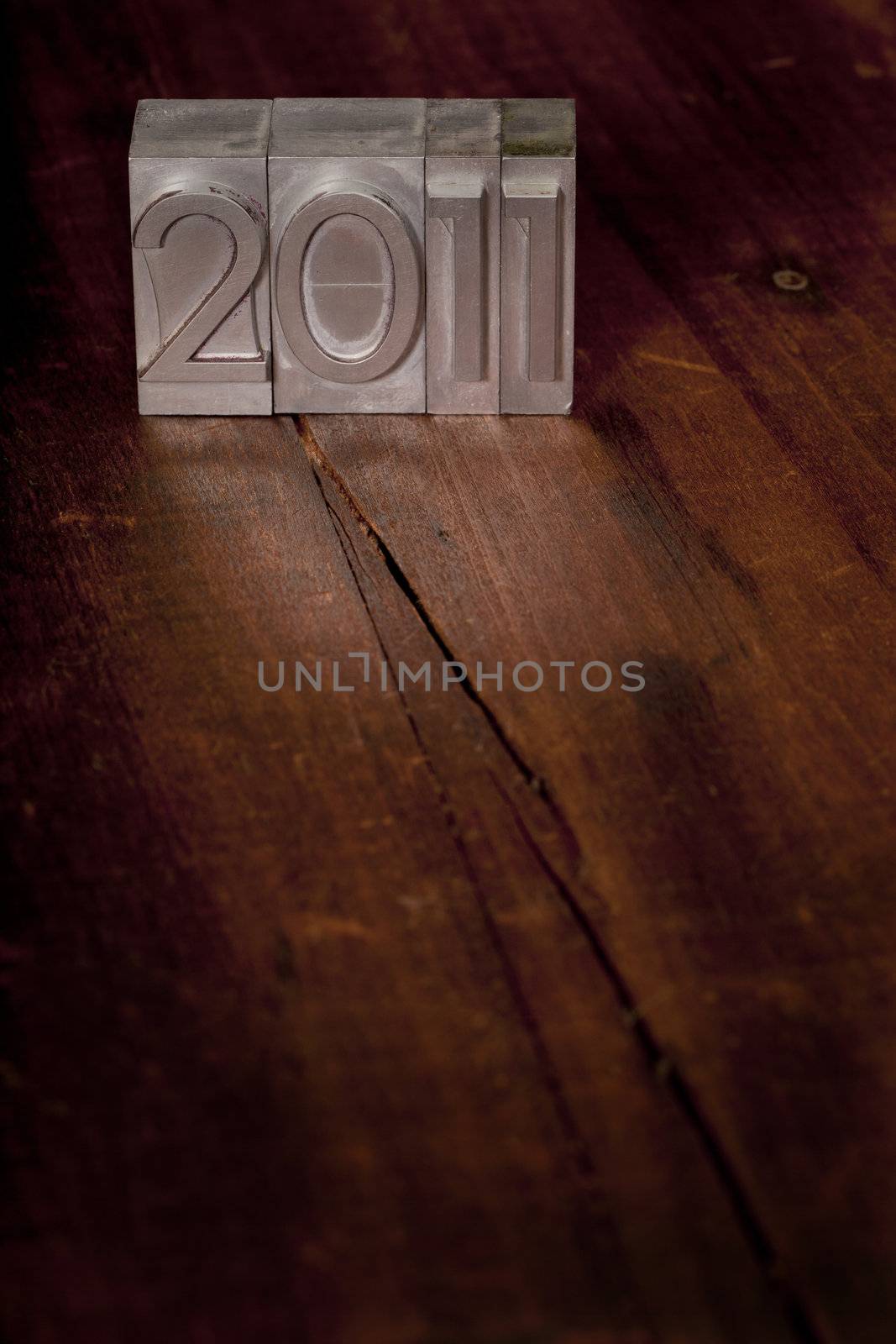 2011 New Year concept - vintage metal letterpress printing blocks on dark grunge wooden surface with scratches and cracks