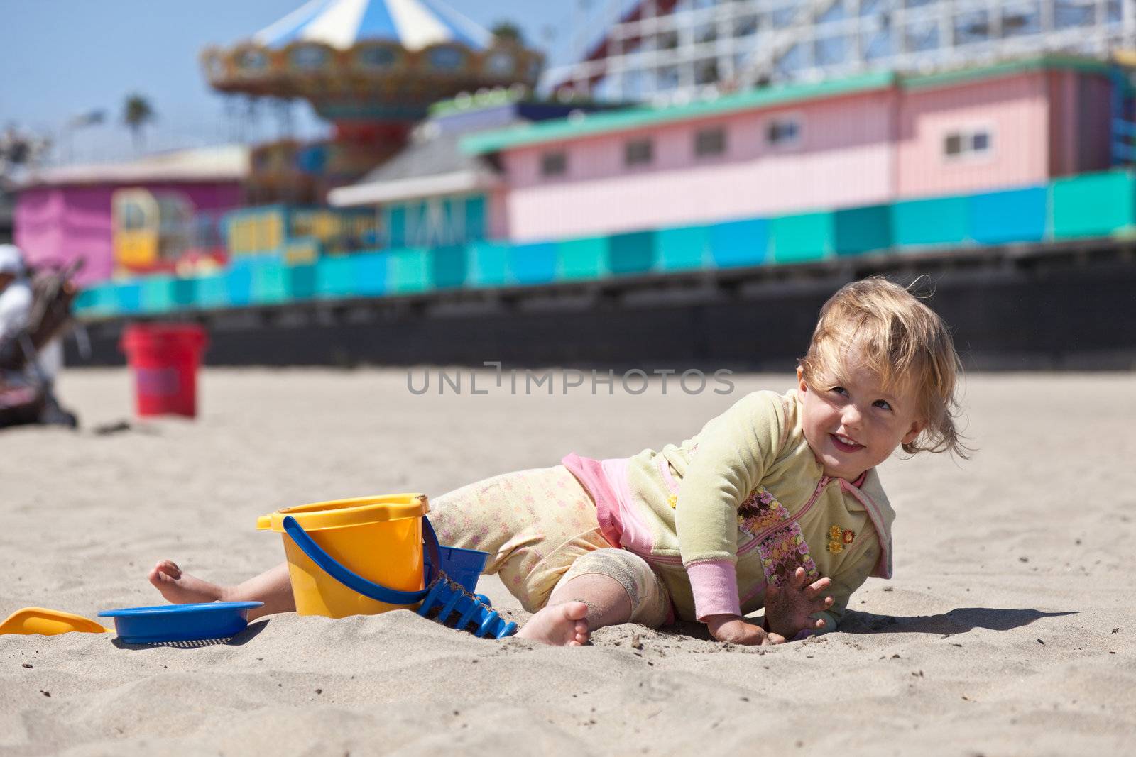 Cute little European toddler girl having fun with sand on the beach.