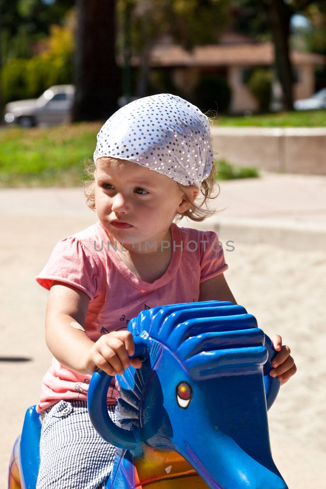 Cute little European toddler girl having fun at the playground in the park.