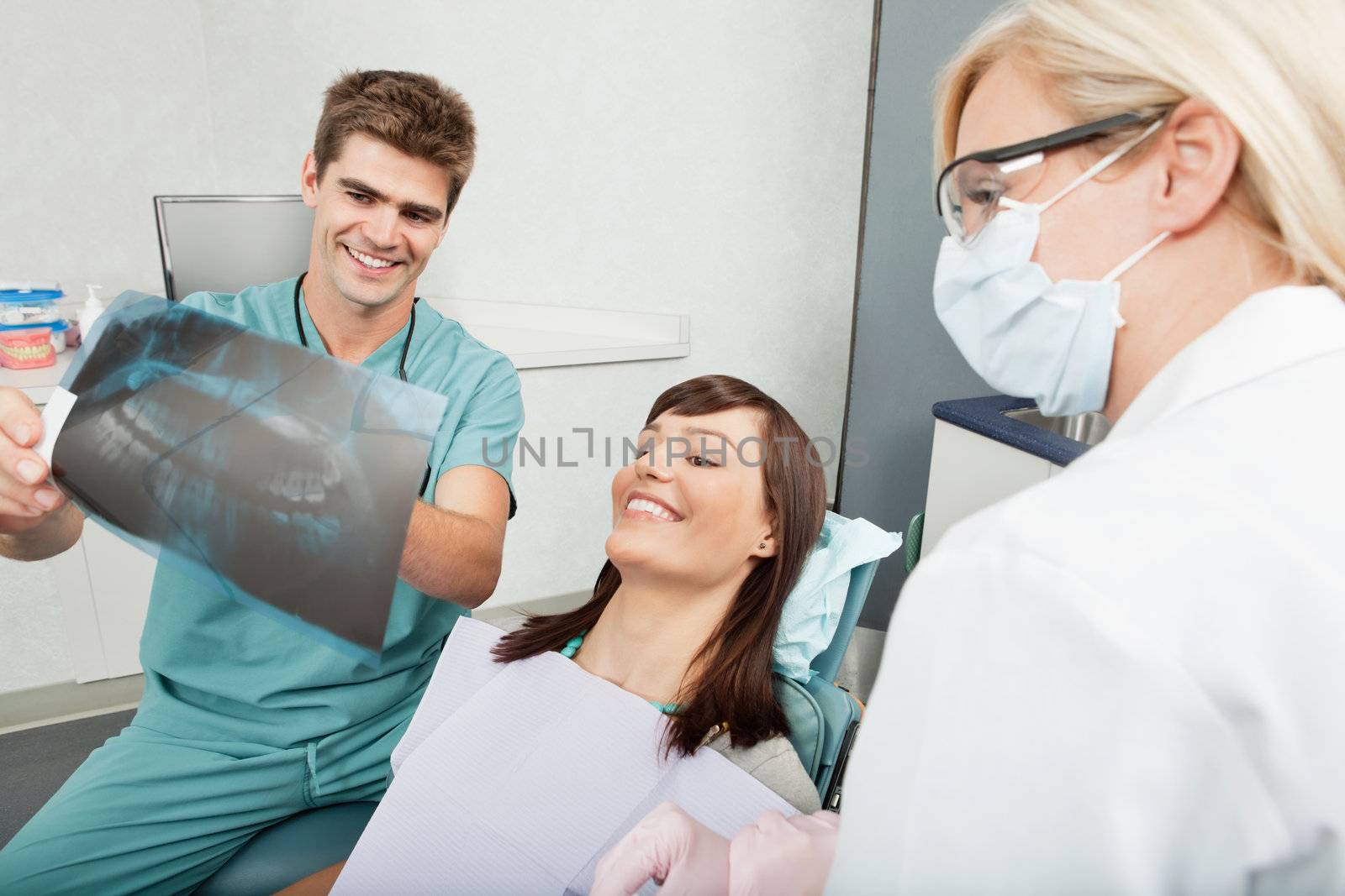 Smiling male dentist explaining the details of x-ray to a beautiful female patient