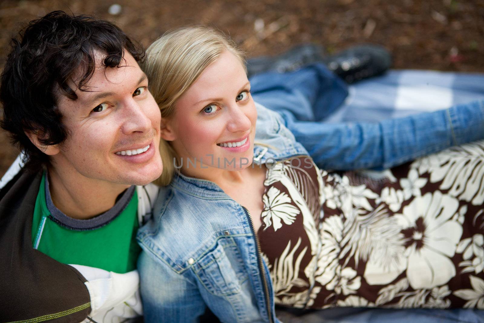 A couple smiling at the camera relaxing outdoors