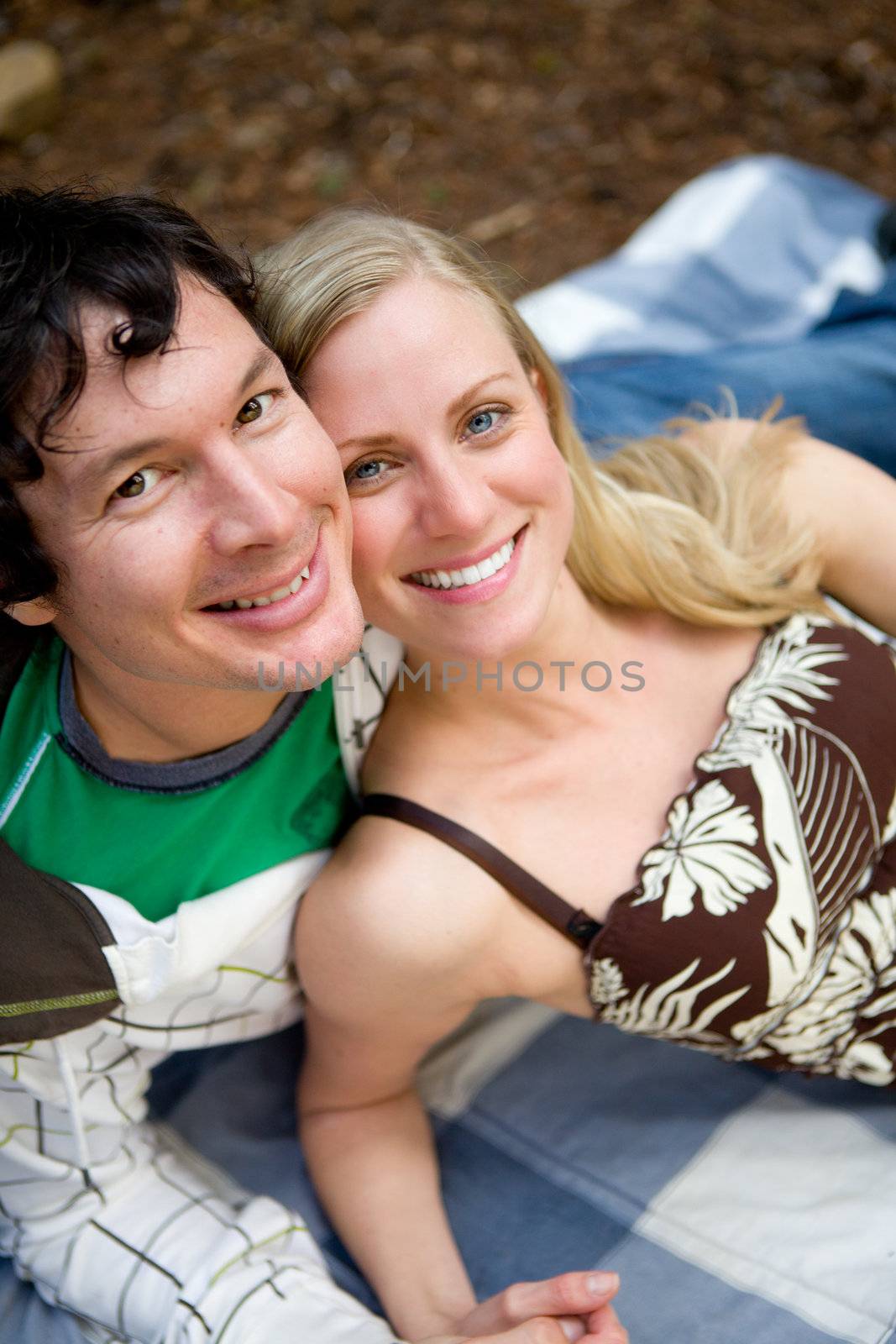 A portrait of a smiling happy couple outdoors on a picnic blanket