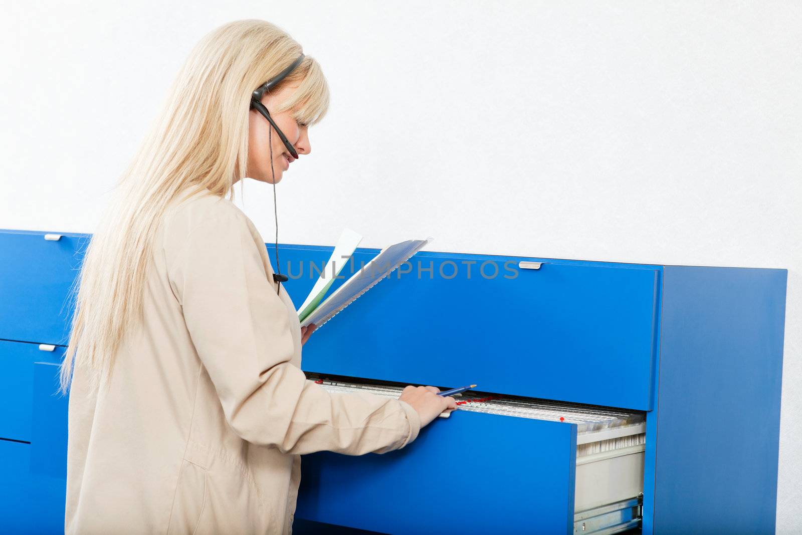 Side view of a young woman searching for documents through a file drawer