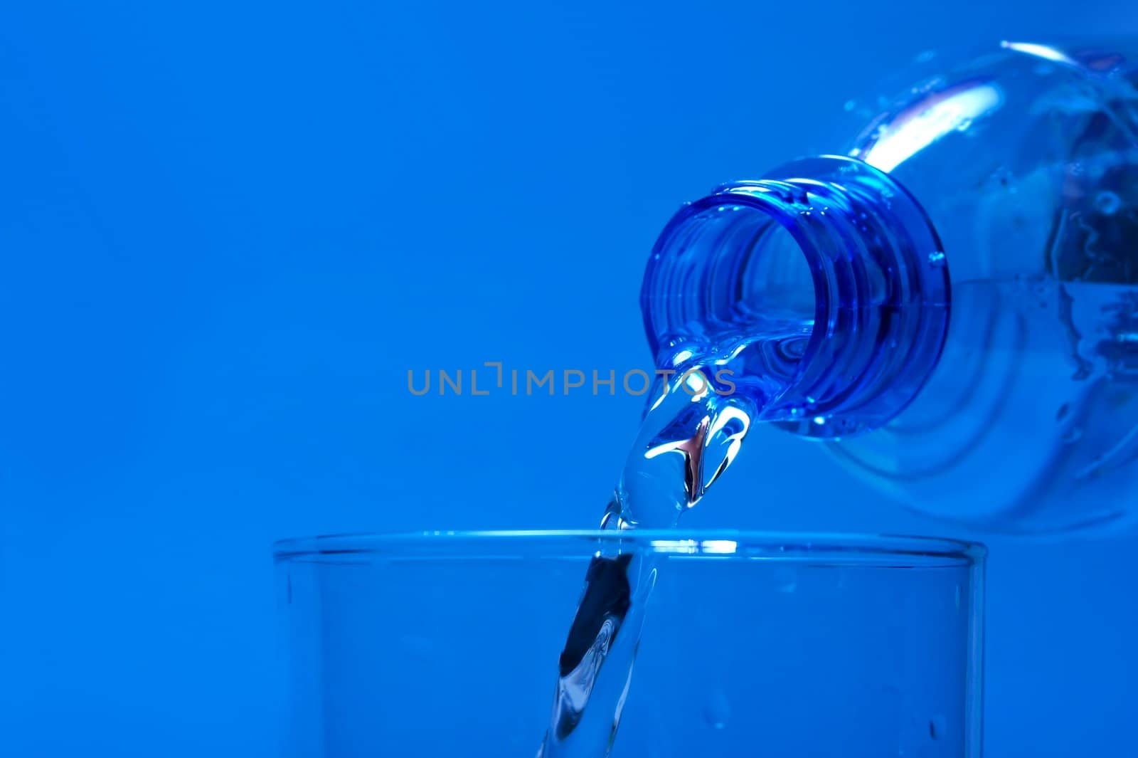 Pouring water from a bottle, blue background