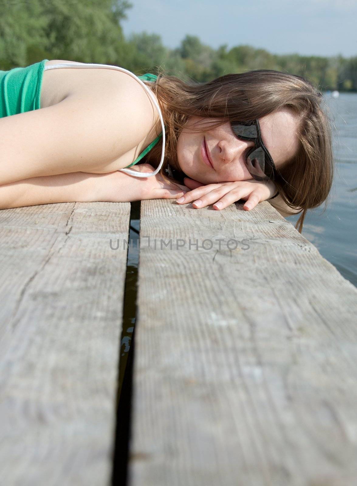 Girl relaxing on a pier in the sunshine