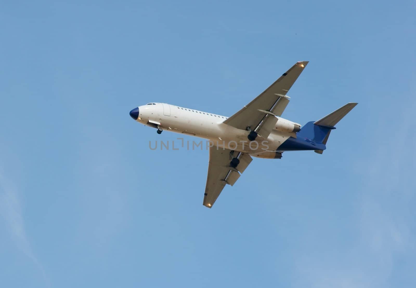 White passenger airplane landing against clear blue sky