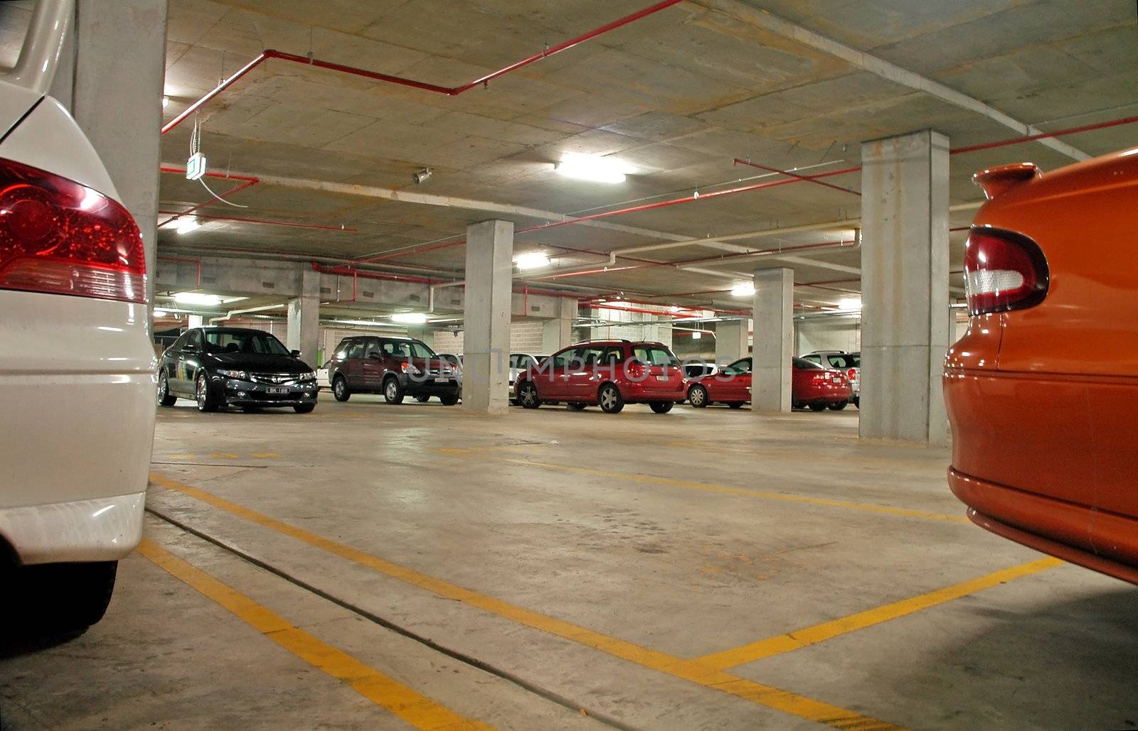 car park floor view, several cars, grey pillars