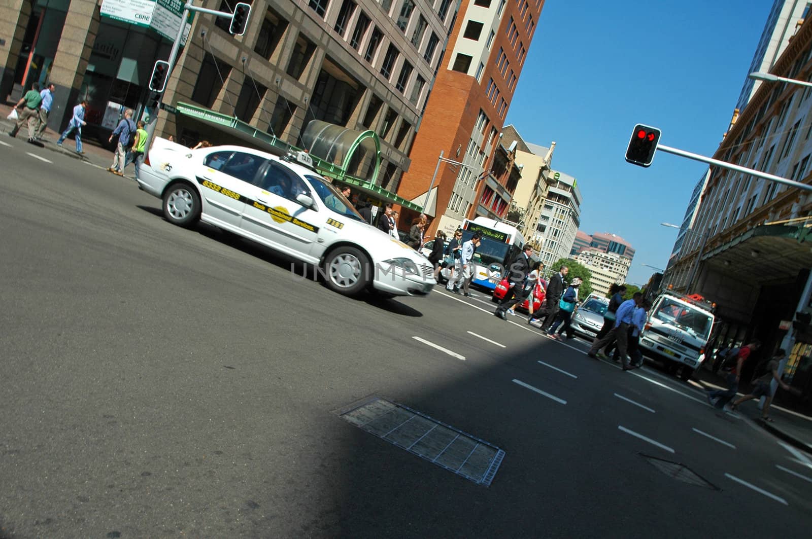sydney traffic, white taxi passing by, walking pedestrians 
