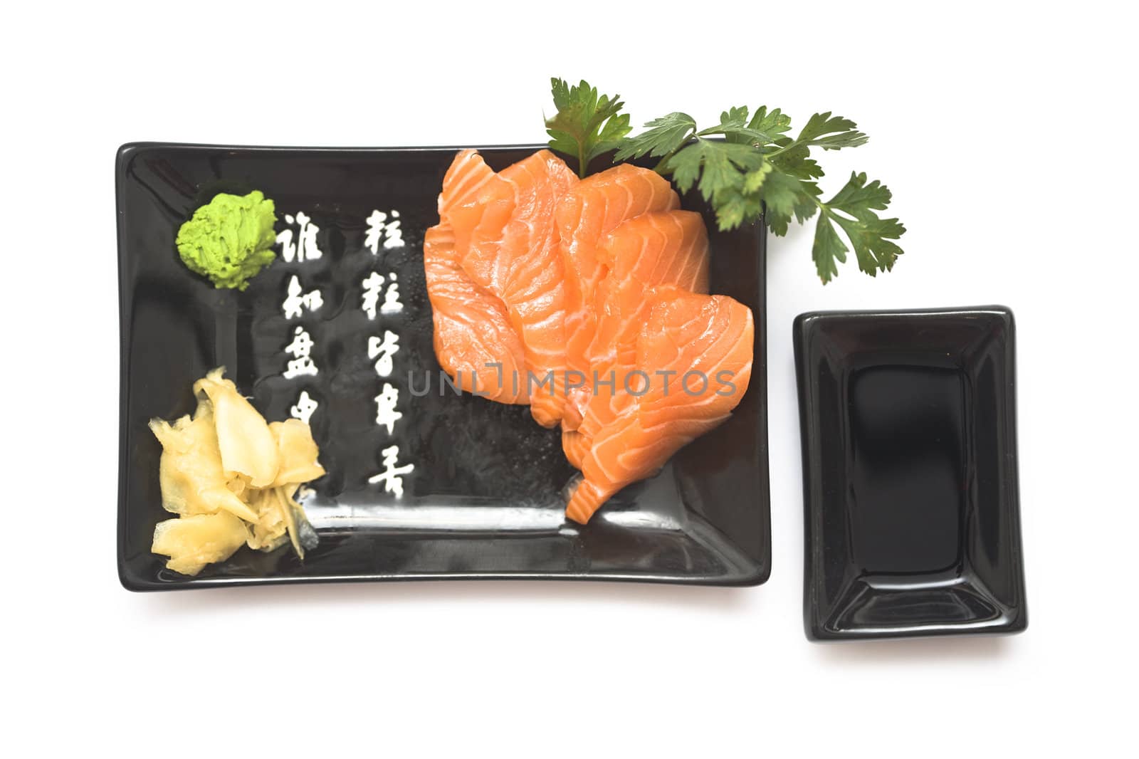 A set of sushi on a black plate with wasabi and gari, isolated on a white background.