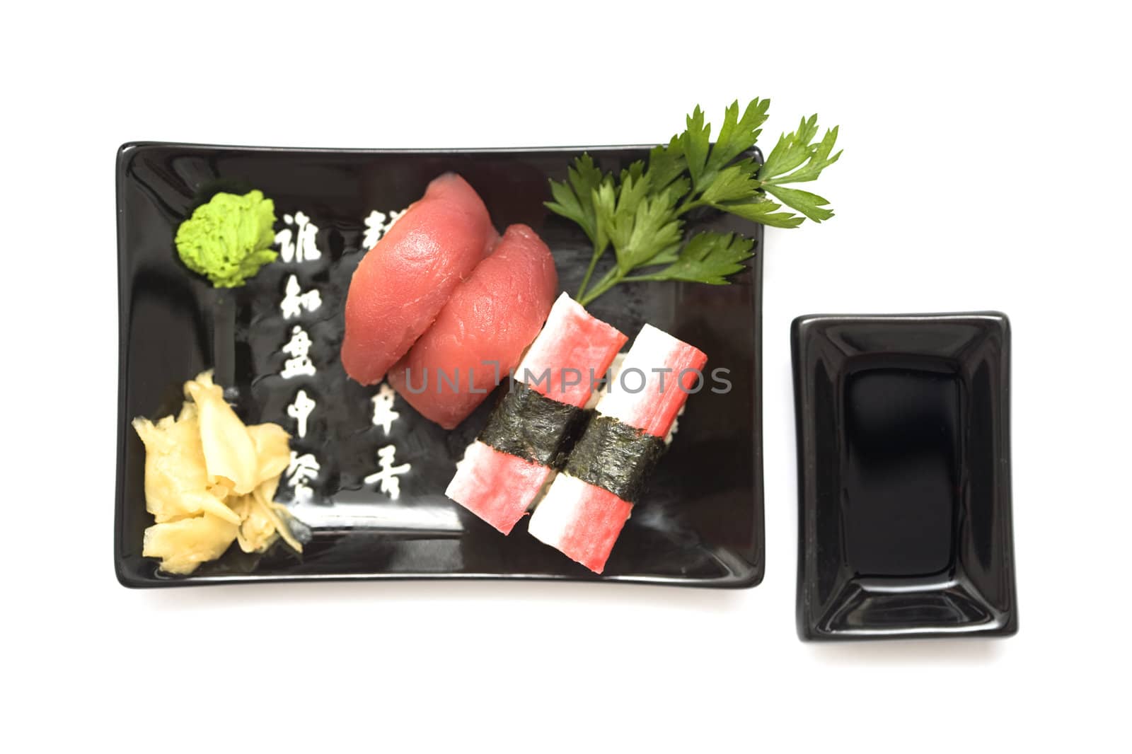 A set of sushi on a black plate with wasabi and gari, isolated on a white background.