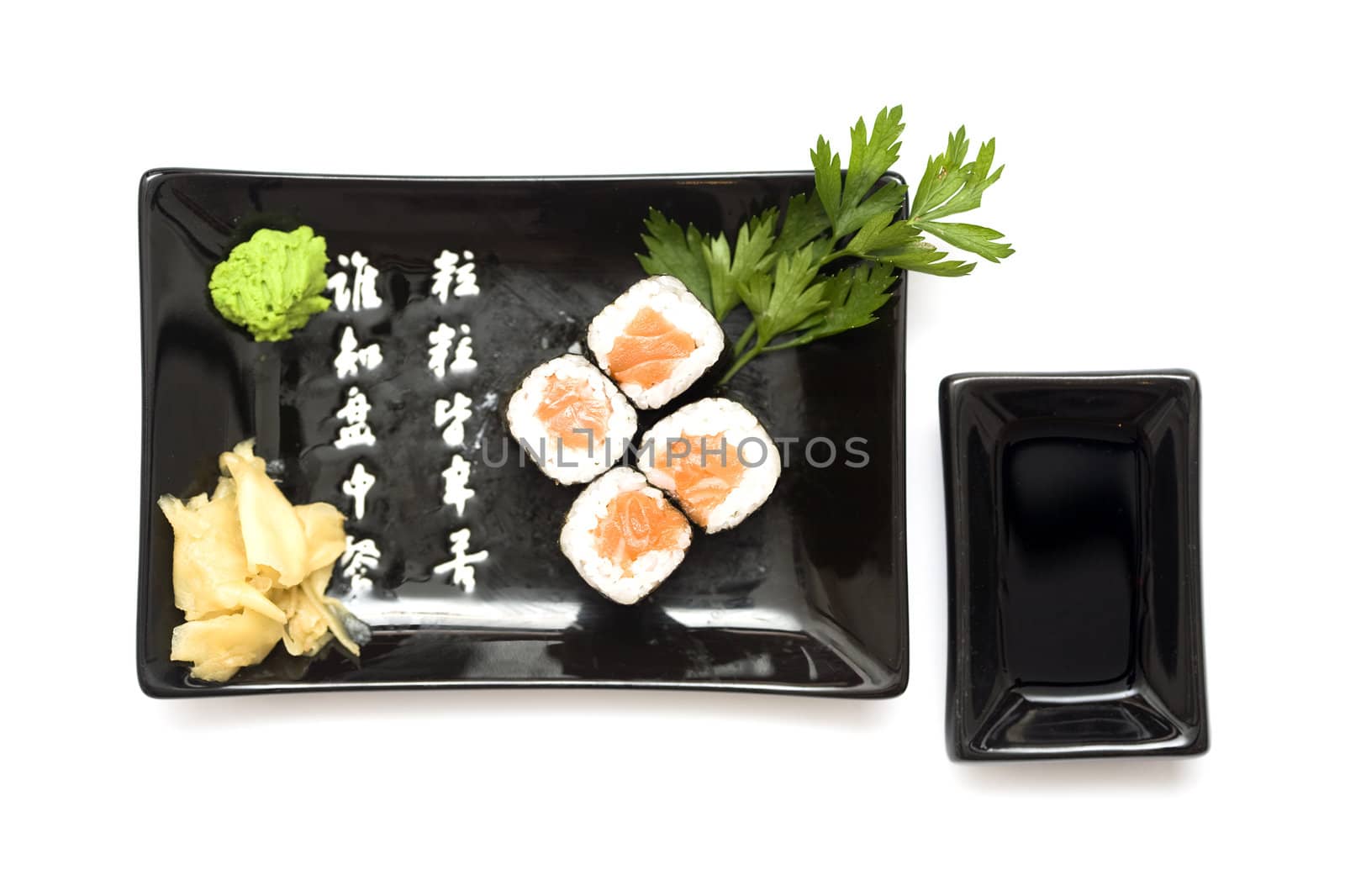 A set of sushi on a black plate with wasabi and gari, isolated on a white background.