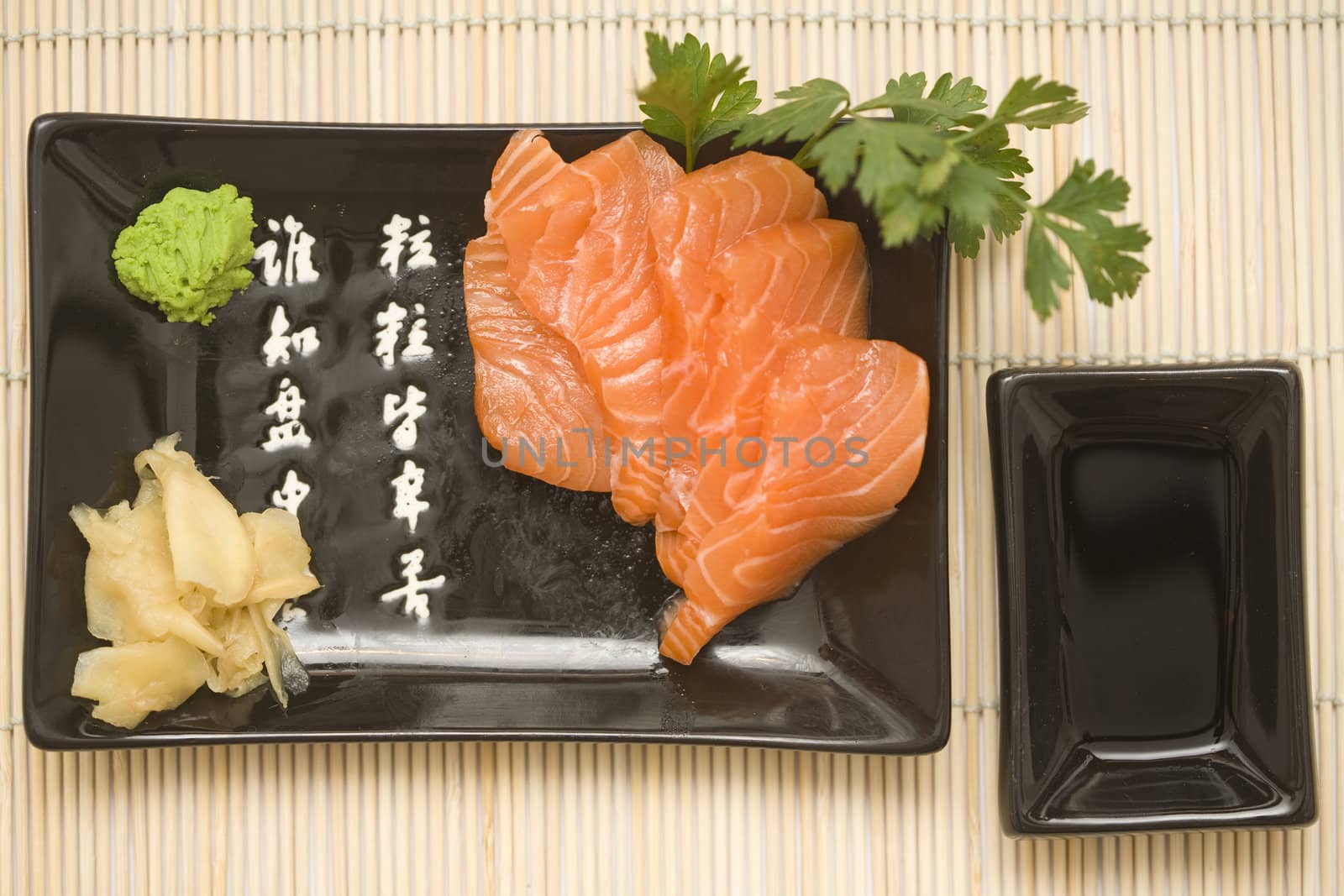 A set of sushi on a black plate with wasabi and gari, on a makisu (bamboo rolling mat).