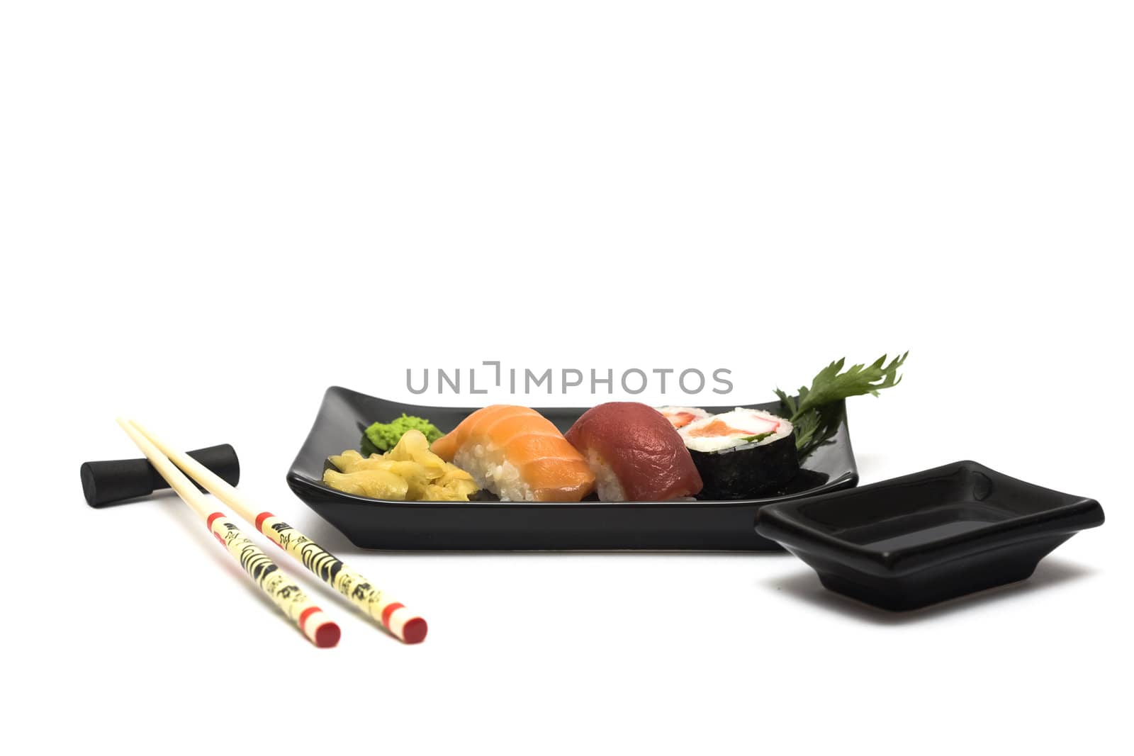 A set of sushi on a black plate with wasabi and gari, isolated on a white background, wish hashi ans soy sauce.