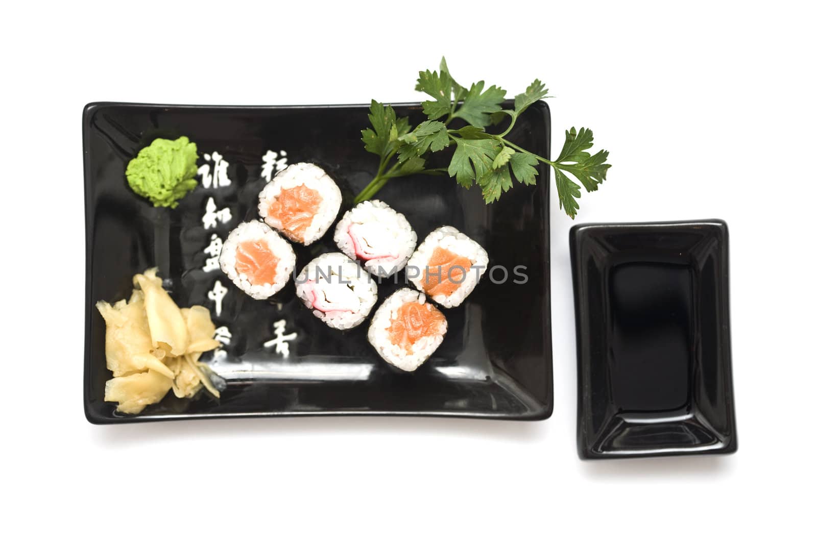 A set of sushi on a black plate with wasabi and gari, isolated on a white background.