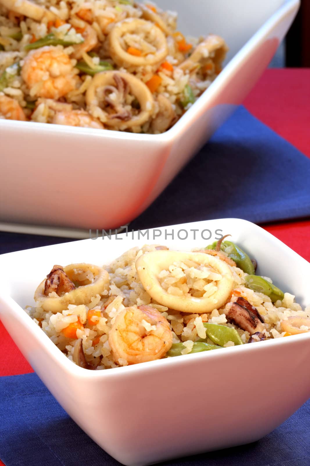 delicious calamari rice with assorted seafood and vegetables served on nice fancy table  