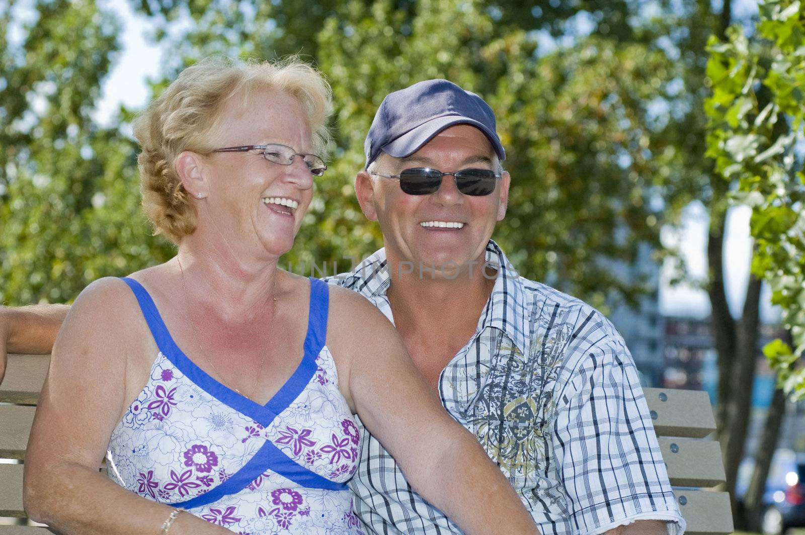 Aged couple sitting on a bench and laughing out loud