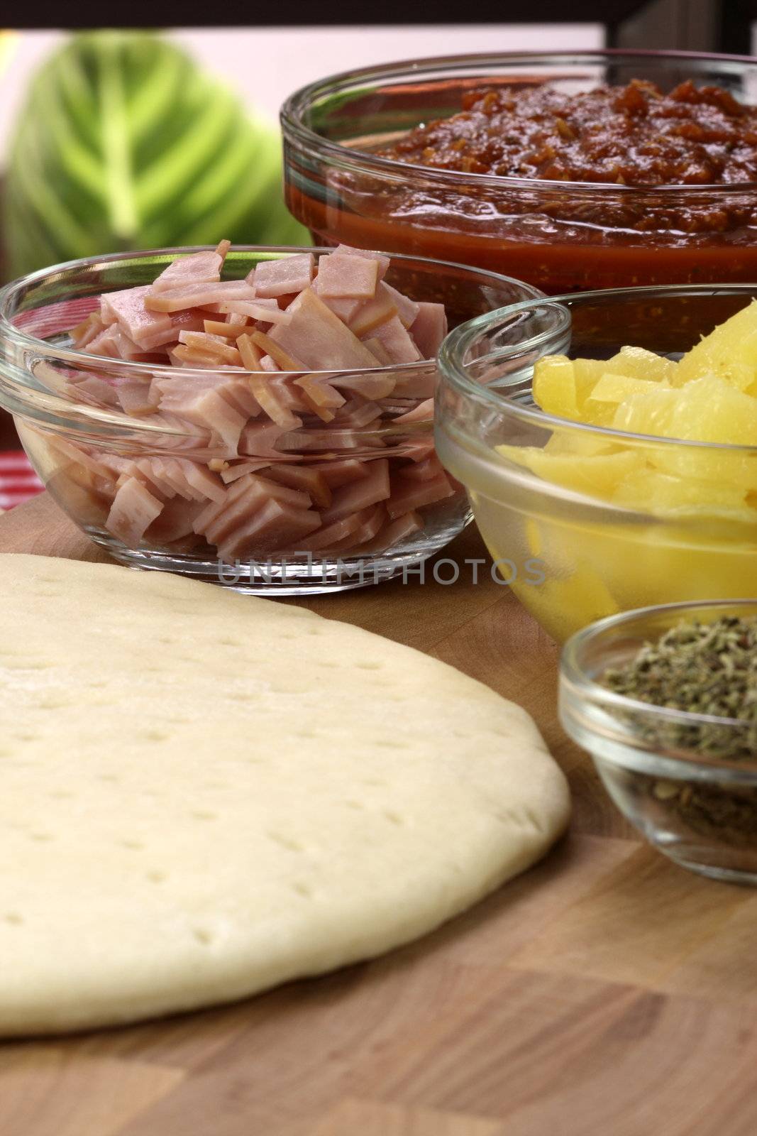 hawaiian pizza ingredients and utensils  on  wood cutting board 
