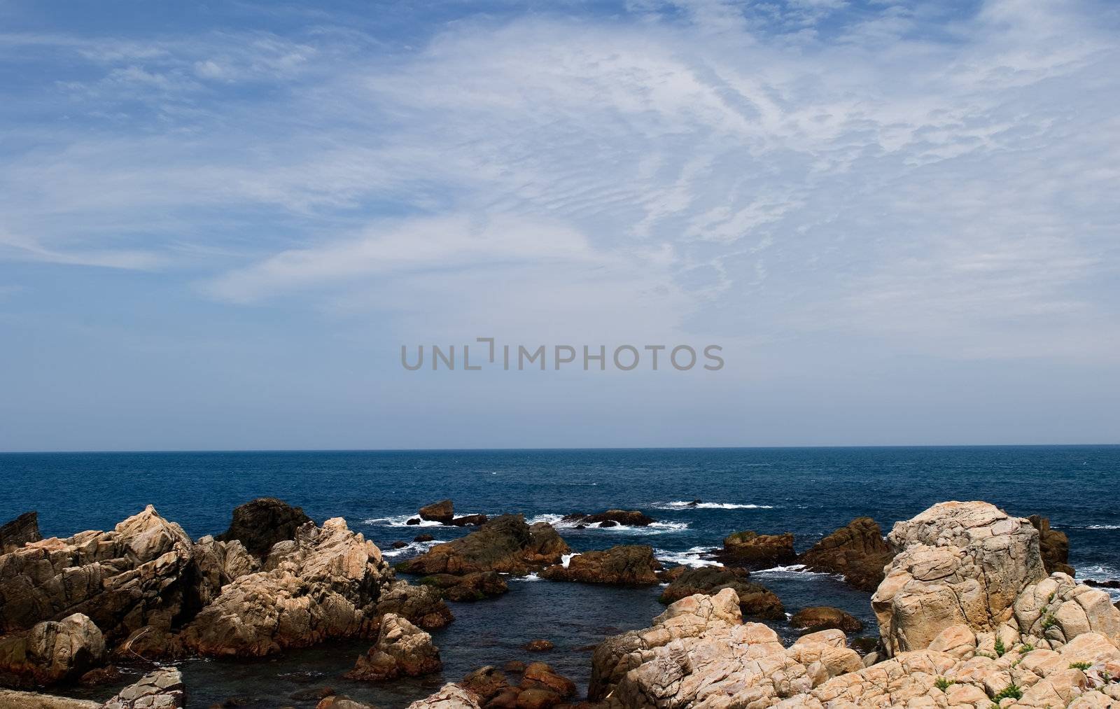 It is a beautiful seascape of rock and blue sea water.