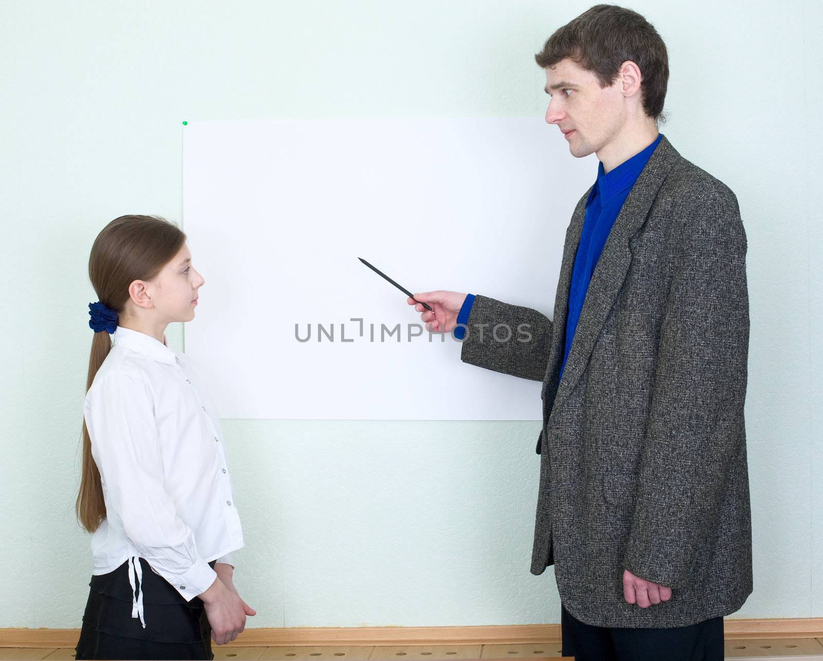 Teacher explains something to the schoolgirl showing on the poster