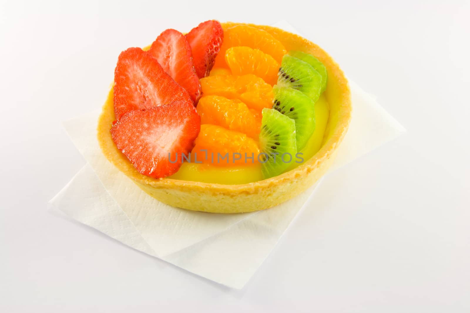 Strawberry, mandarin and kiwi custard fruit tart on a napkin with a white background