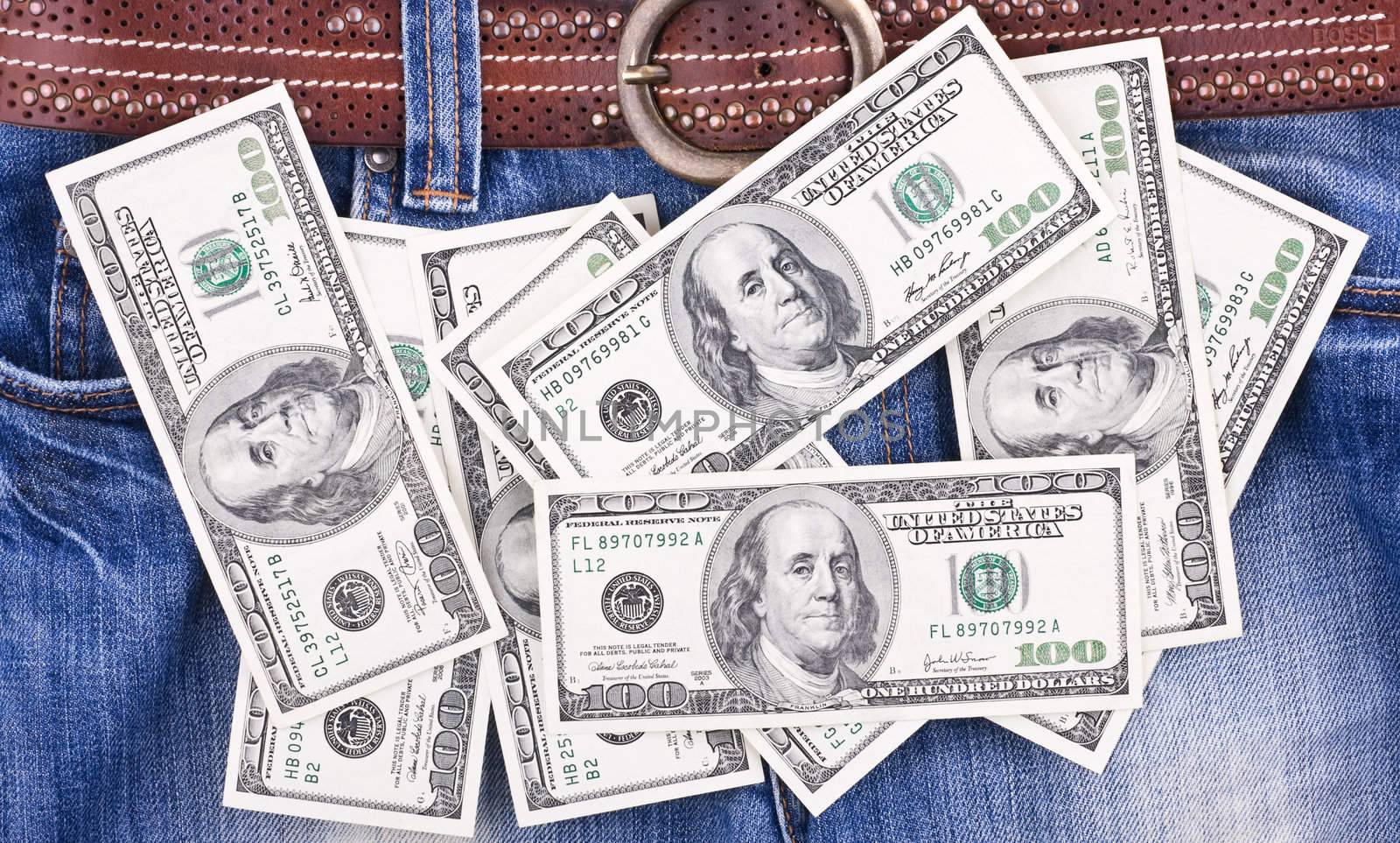 Many hundred dollar bills lying on blue jeans by rozhenyuk