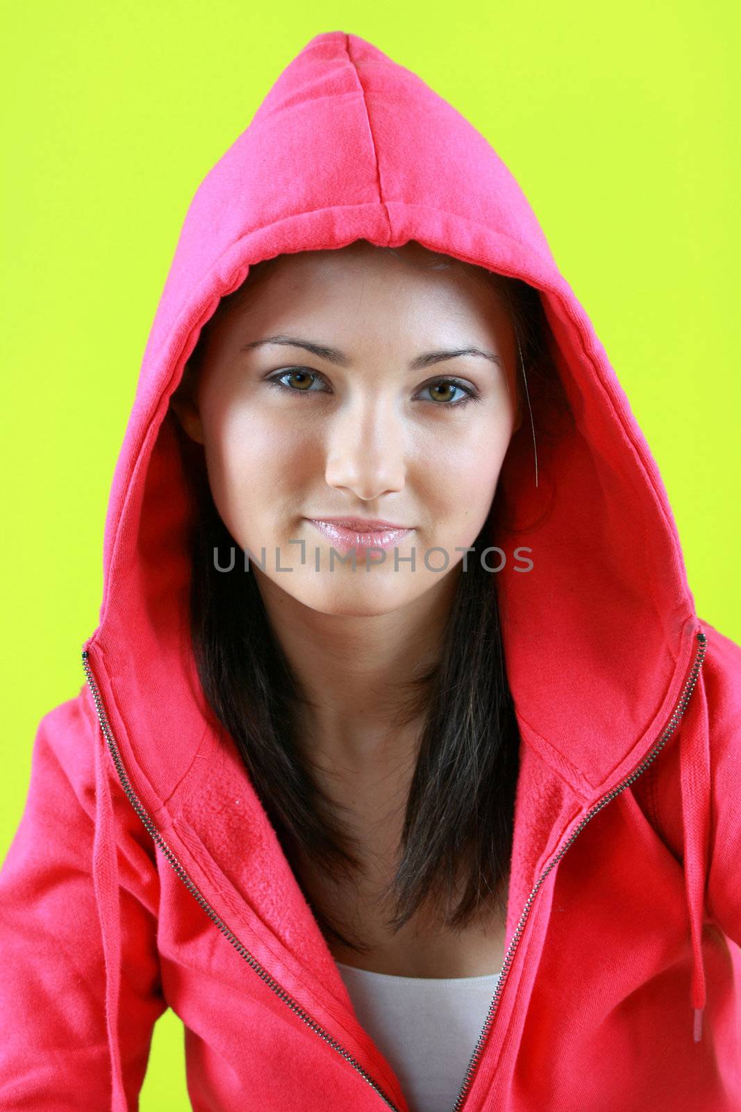 Portrait of young beautiful teen girl in pink hood on green background