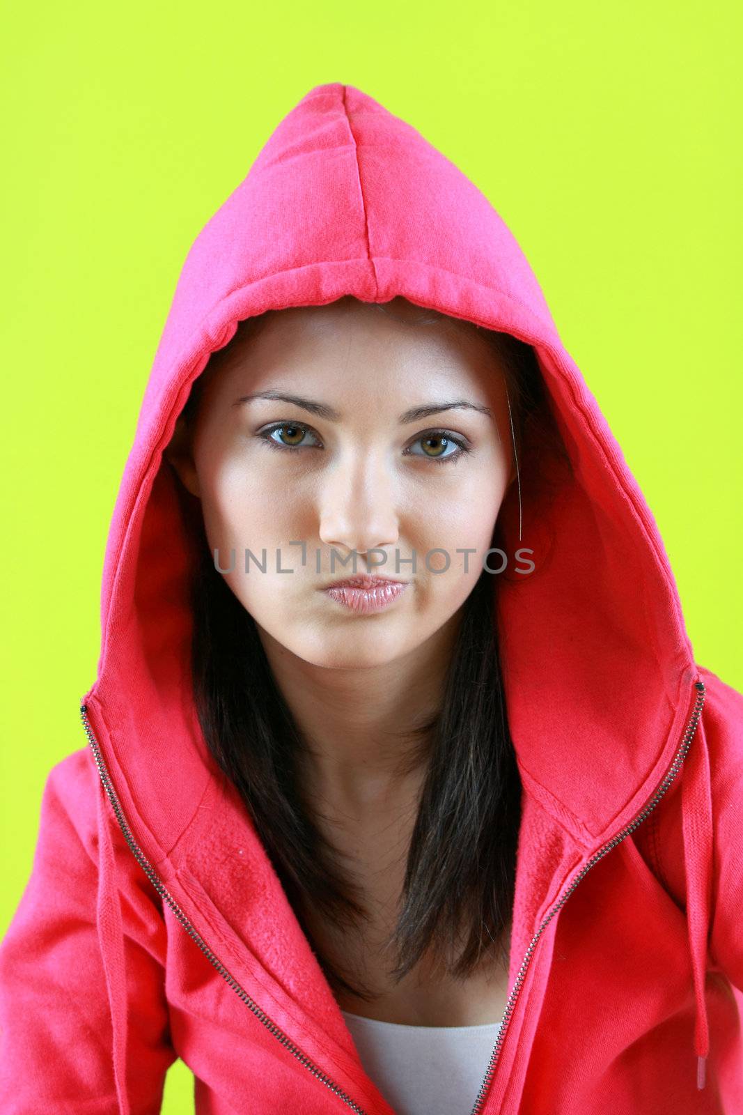 Portrait of young beautiful teen girl in pink hood on green background