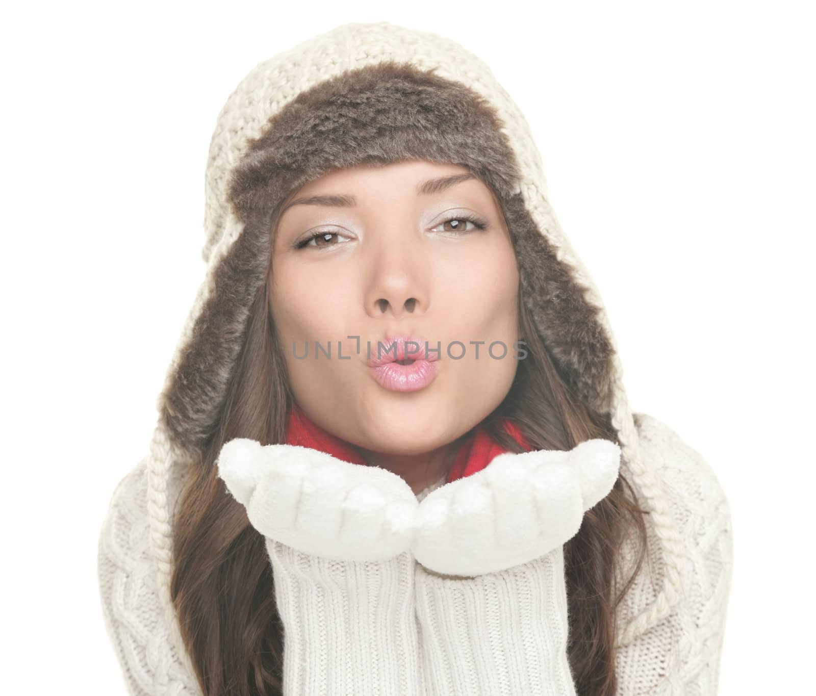 Winter woman isolated blowing kiss. Beautiful young lady in warm winter hat and clothing blowing a kiss to the camera.  Mixed Asian / Caucasian woman isolated on white background.