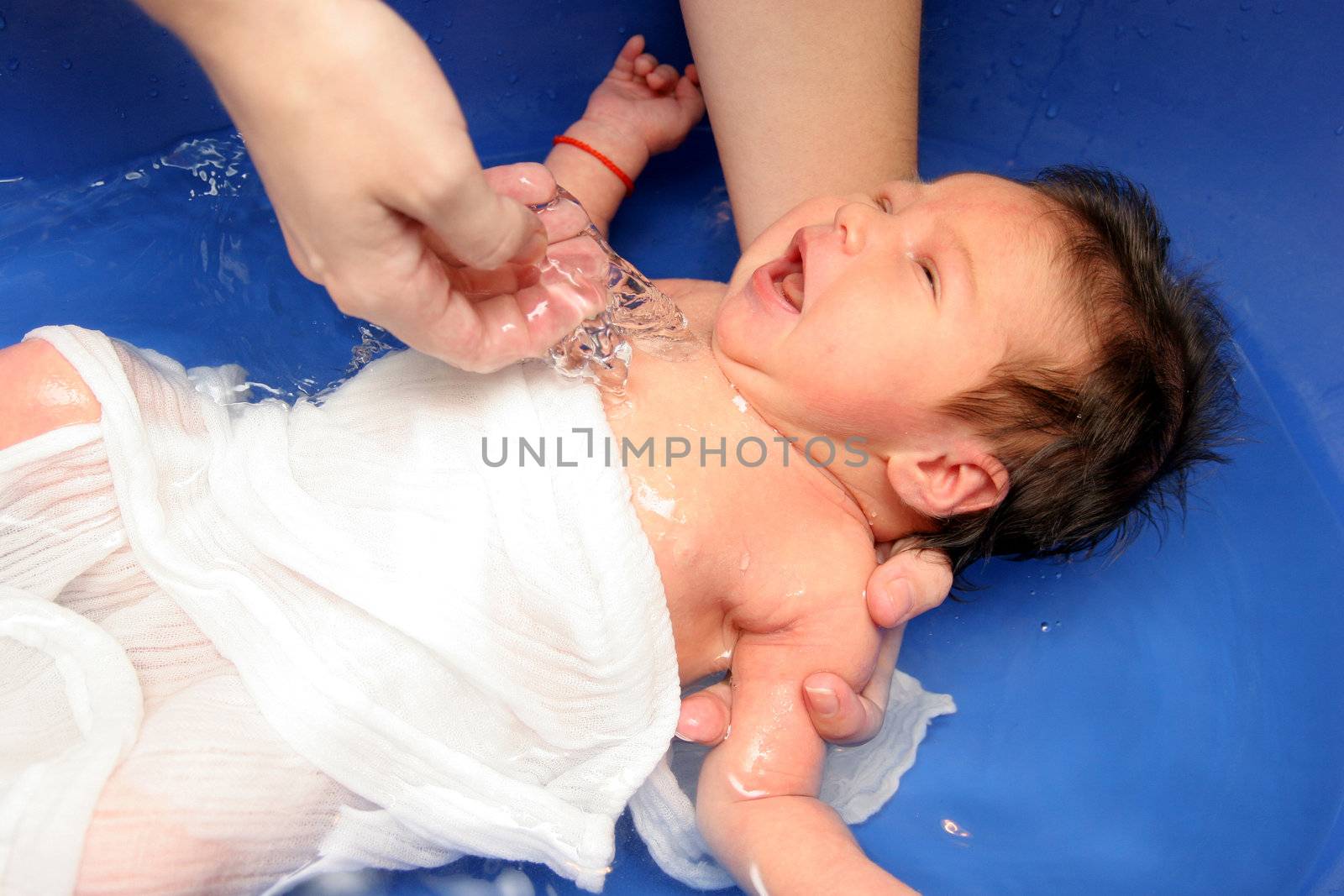 A baby girl in a bathtub at her mother