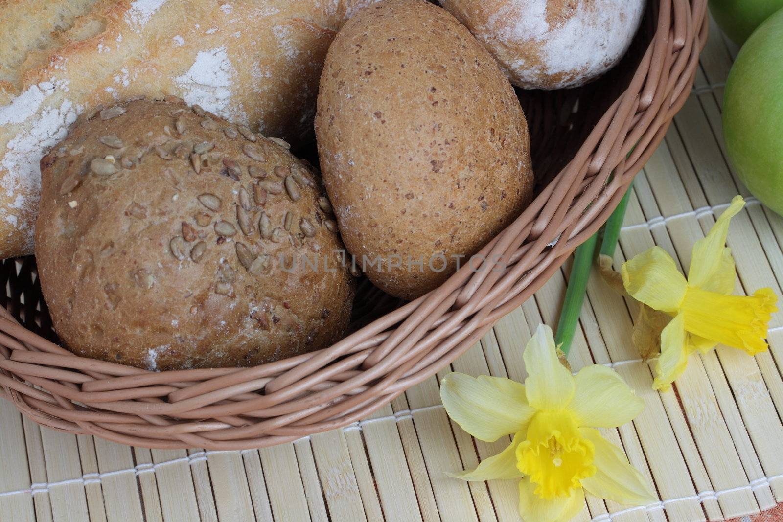 Basket of various fresh baked bread on wooden table by BDS
