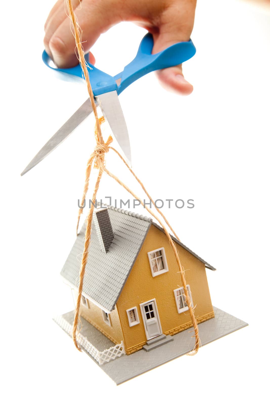 Hand with Scissors Cutting String Holding House Isolated on a White Background.