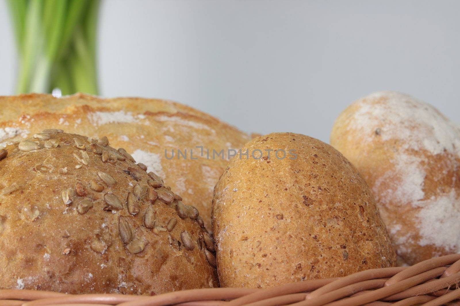 Basket of various fresh baked bread on wooden table by BDS