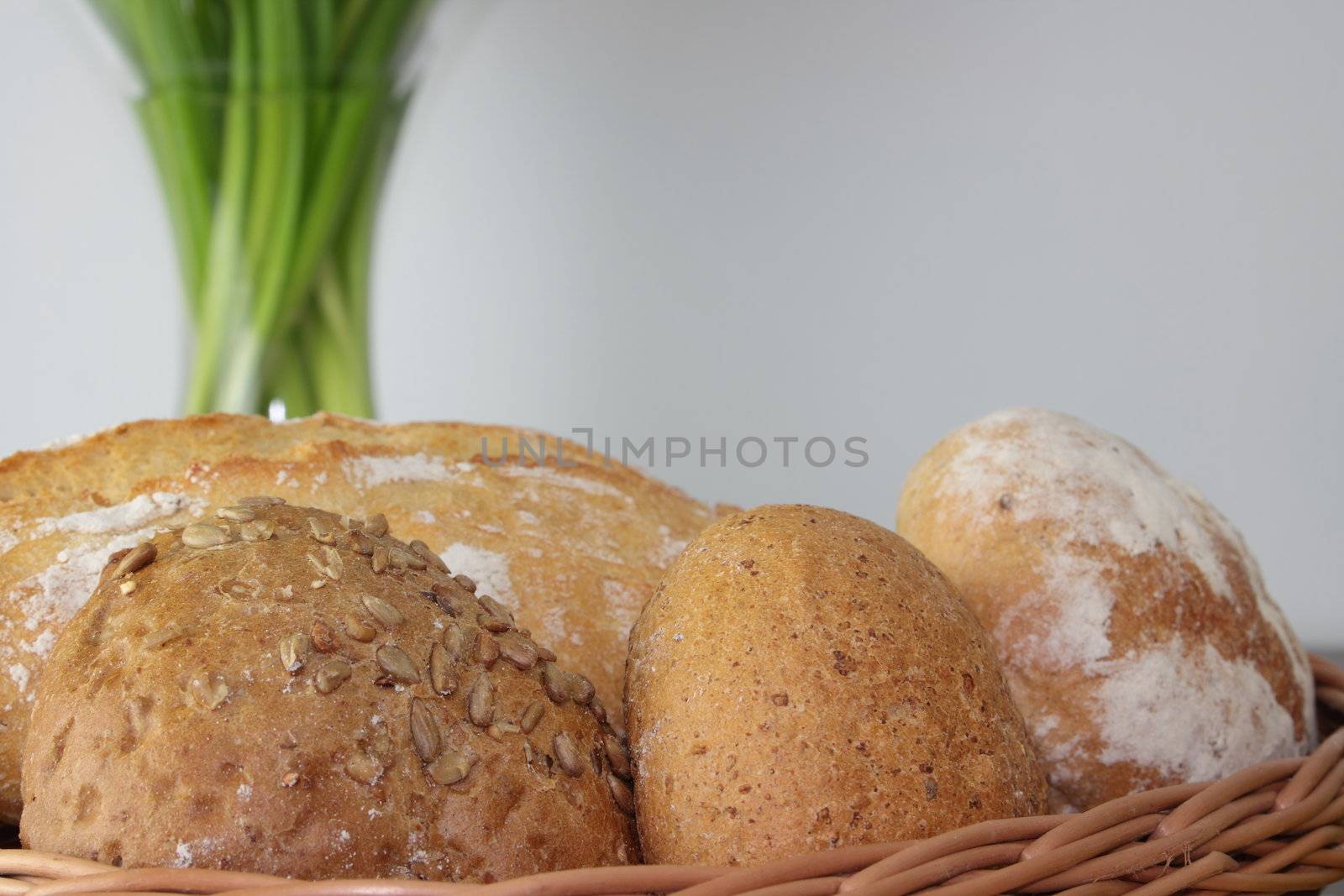 Basket of various fresh baked bread on wooden table by BDS