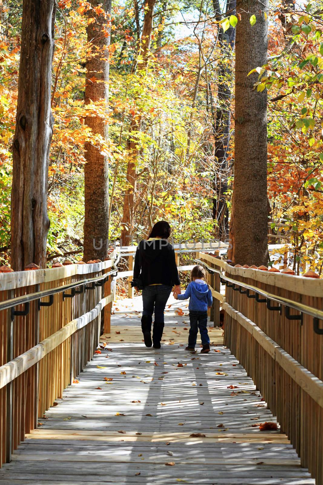 Young mother walking with little girl in a beautiful autumn park.