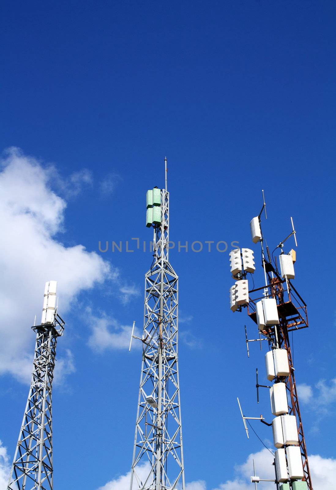 Three cellular antennas against blue sky.