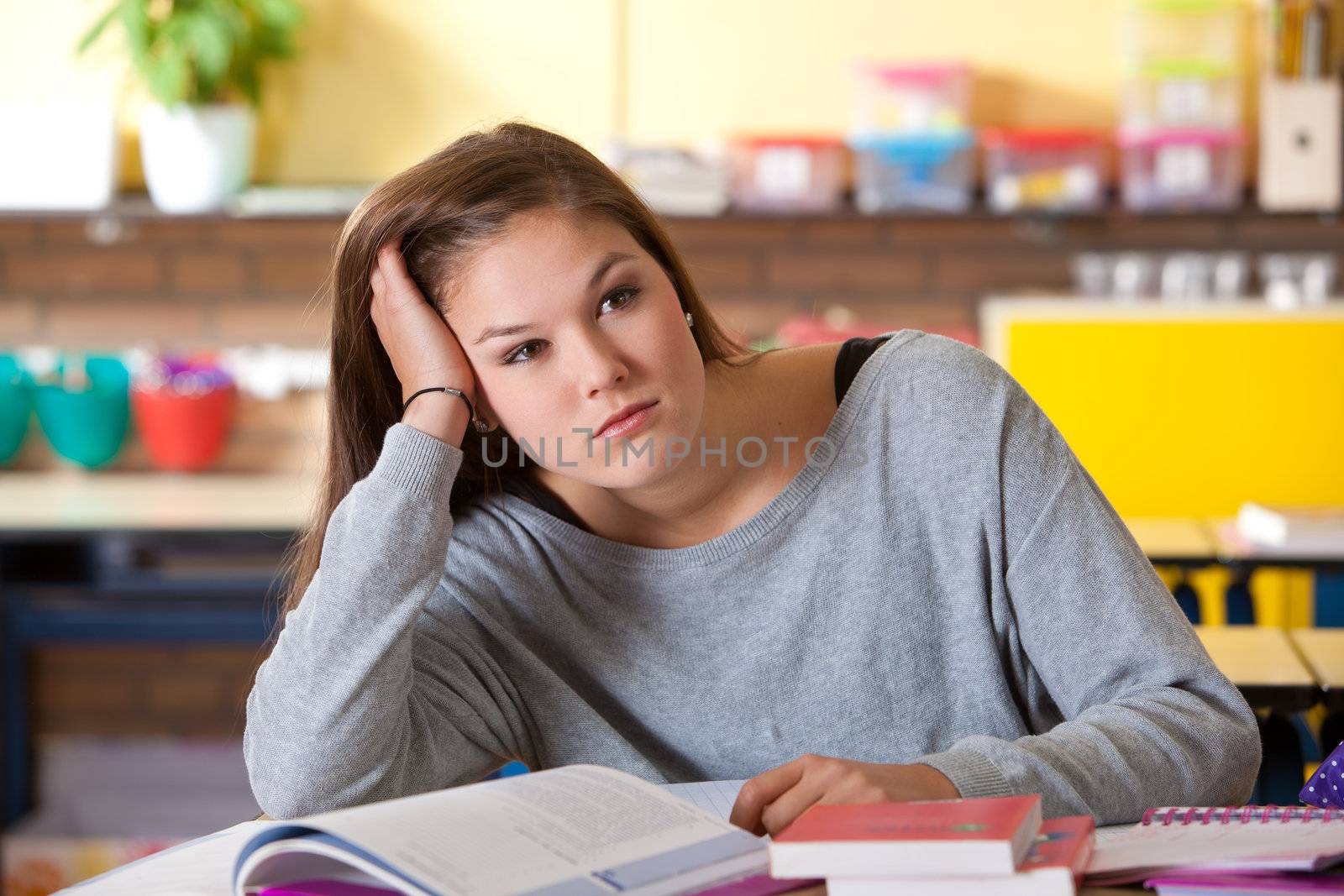 Attractive young teenager dreaming away in the classroom looking bored