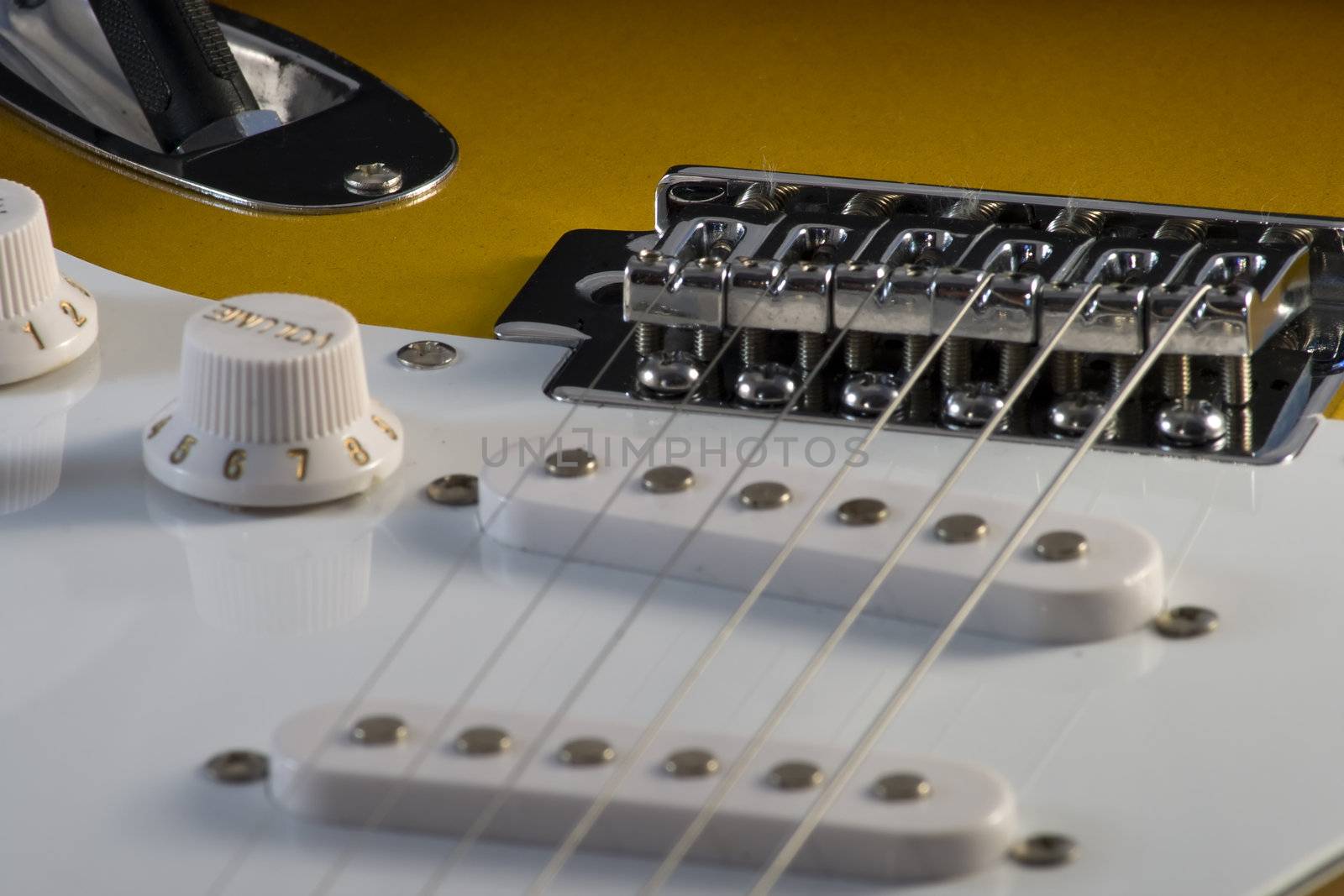 Closeup of electric guitar Stratocaster-type, white and sunburnt, with strings