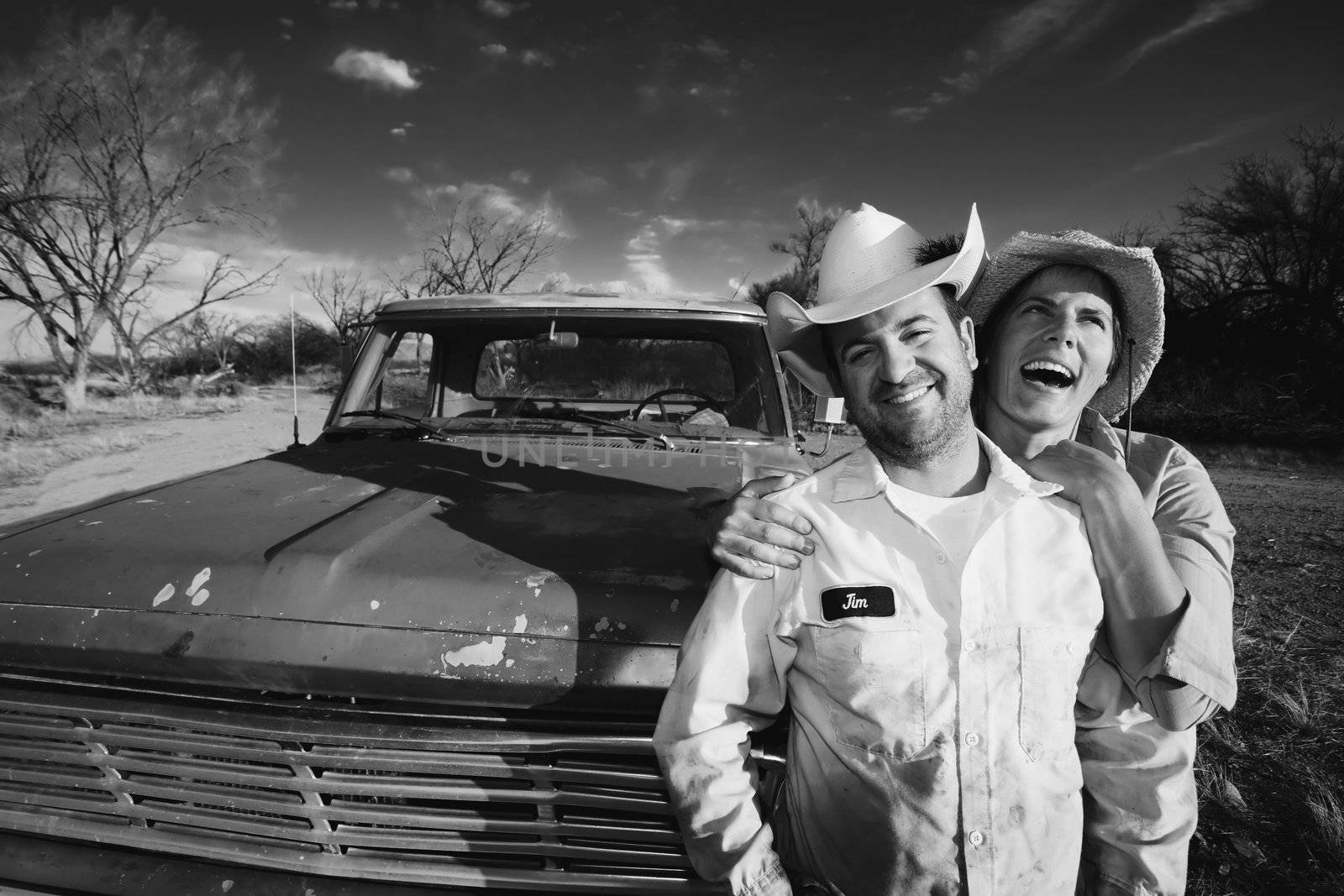 Man and woman in cowboy hats with old truck