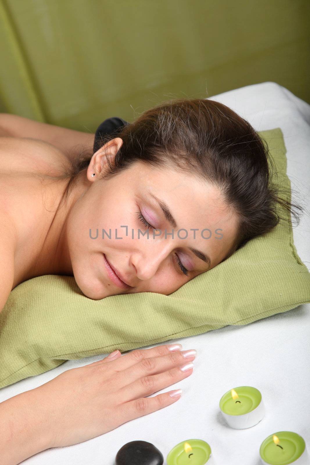 young woman lying on a massage table after or during a massage wtih candles in the 