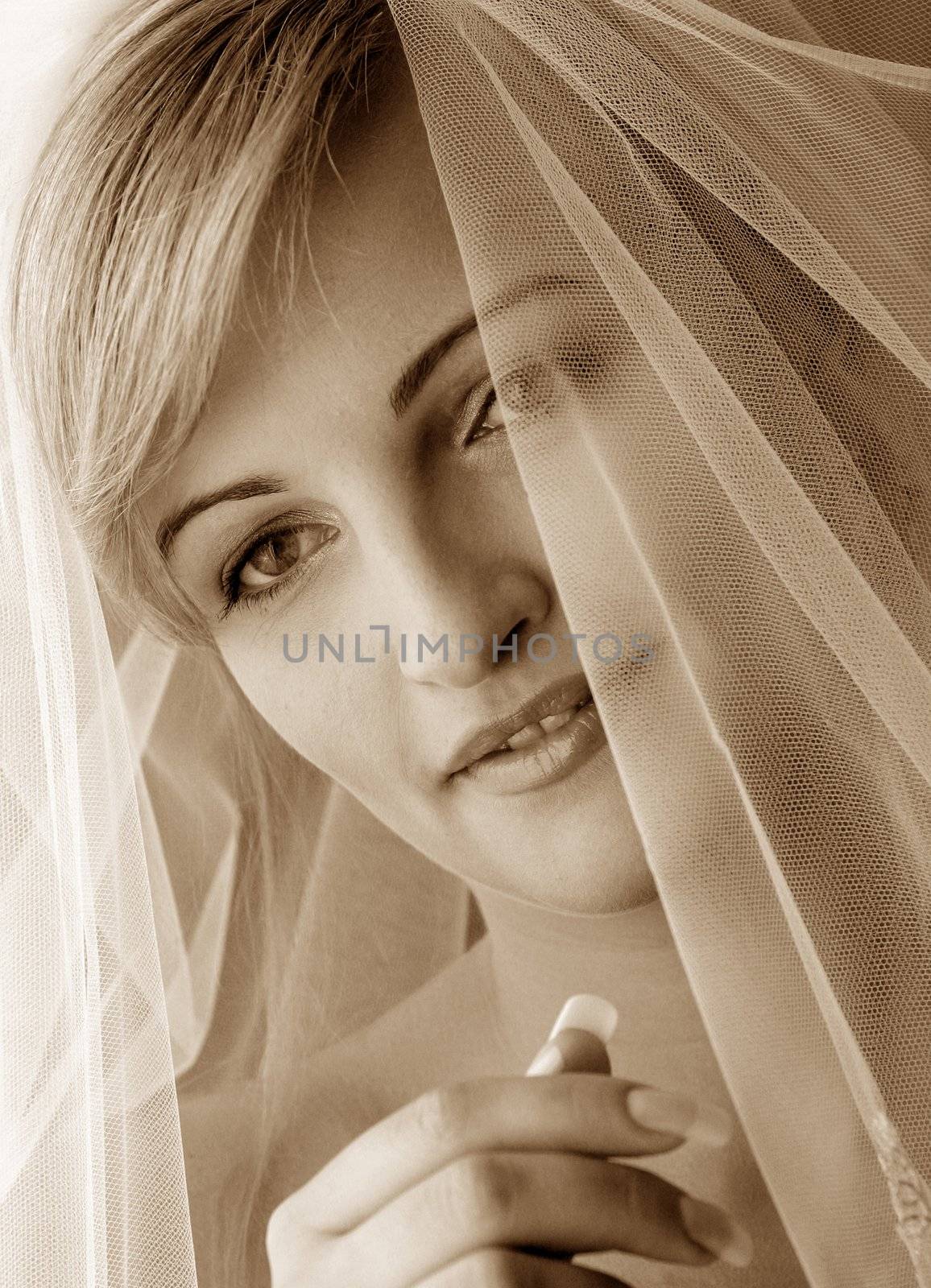 Sepia portrait of beautifusmiingl bride with veil.